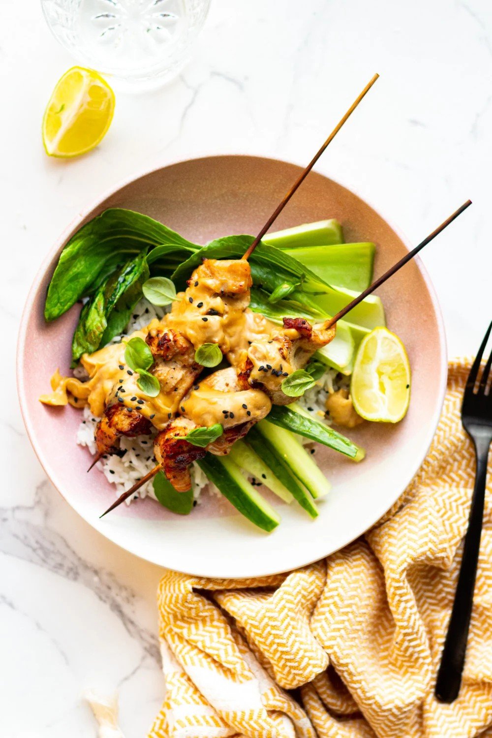 Satay chicken skewers with rice, cucumber, and bok choy