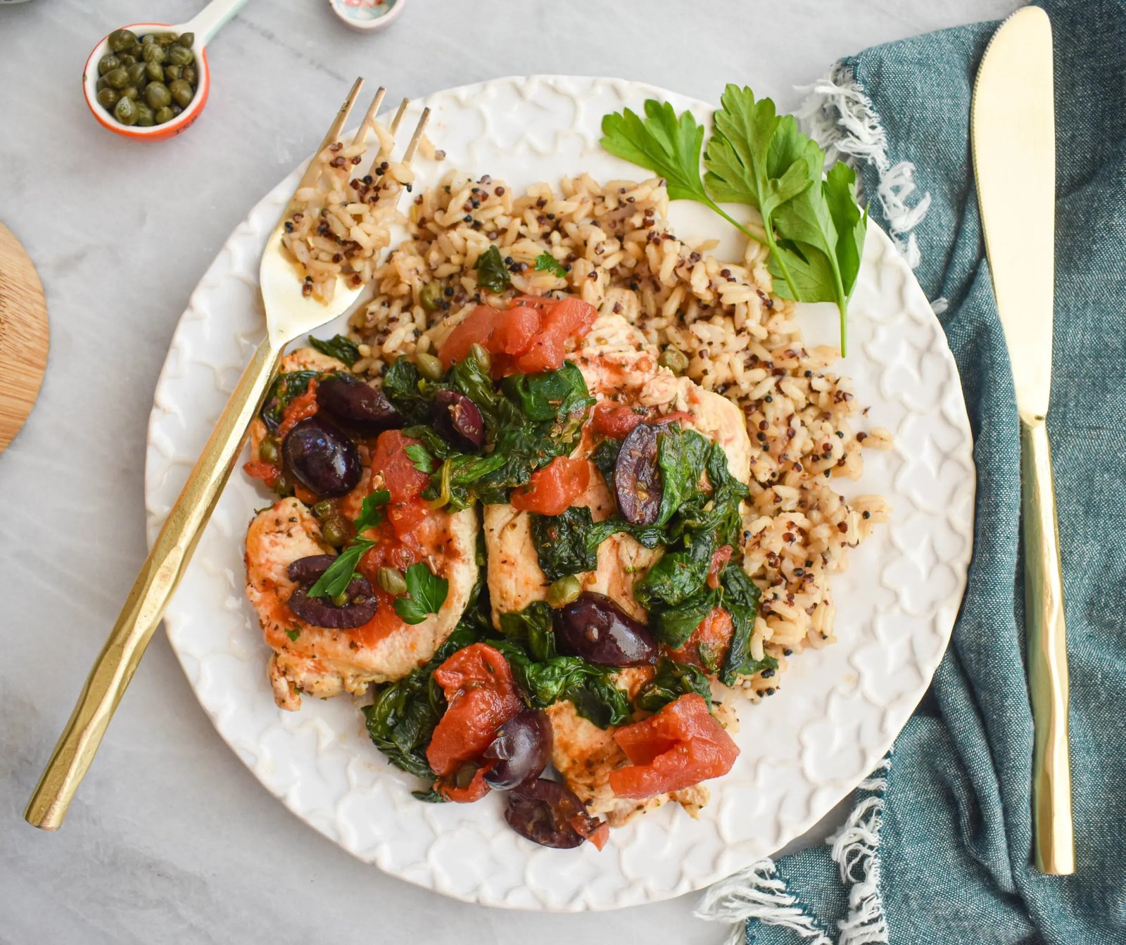 Mediterranean chicken with tomatoes, olives, and spinach in a skillet